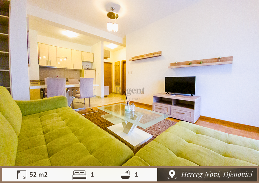 Dnevna soba u jednosobnom stanu na dan, herceg novi. zelena sofa, stakleni sto, tv, opremljena kuhinja i trpezarijski sto iza